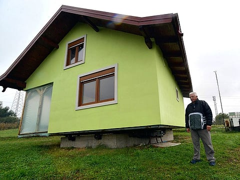 Vojin Kusic's stands in front of his rotating house in a town of Srbac, northern Bosnia.
