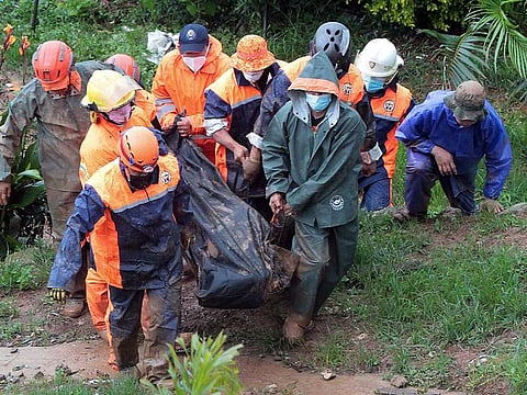 Rescuers carry the body of a victim caught in a landslide caused by Tropical Storm Kompasu in Baguio city, northern Philippines on Tuesday Oct. 12, 2021. A number of people have been killed and others were reported missing in landslides and flash flood set off by a storm that barreled through the tip of the northern Philippines overnight then blew away Tuesday, officials said.