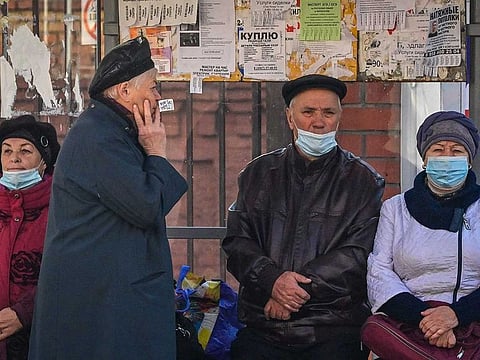 People wearing face masks wait for a bus at a bus stop in the town of Serpukhov some 95 kilometres outside Moscow on October 14, 2021. Russia on October 14, 2021 reported a pandemic high for both new coronavirus infections and fatalities over 24 hours.