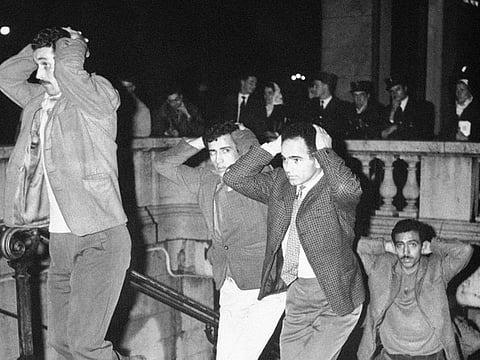 In this October 17, 1961 file photo, Algerians come out of Paris subway station with their hands on their heads after being arrested in Paris for failure to obey curfew imposed on Algerians.
