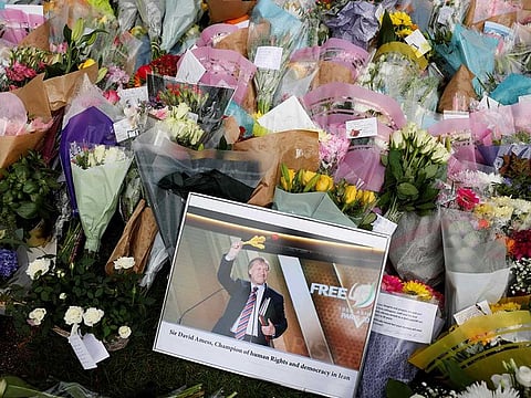 A photograph of Conservative British lawmaker David Amess is seen amid floral tributes left at the scene of the fatal stabbing of Amess, at Belfairs Methodist Church in Leigh-on-Sea, a district of Southend-on-Sea, in southeast England on October 16, 2021.