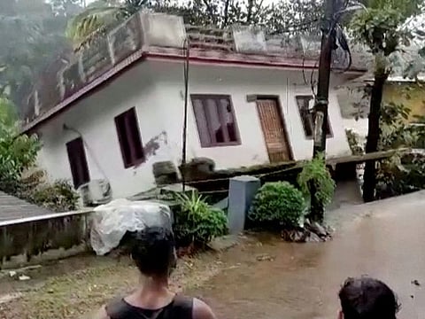 People watch a house being washed away in river due to strong current in Kottayam