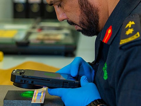 A Dubai Police official using the smart device to digitally capture fingerprints