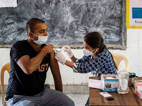 A health worker inoculates a man during a vaccination drive against coronavirus inside a school in New Delhi, India, Wednesday, Oct. 20, 2021.