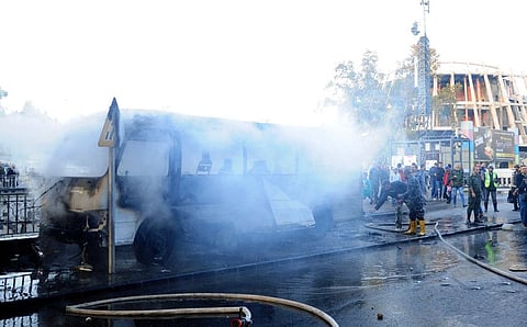 Civil defence members put out a bus fire at the site of a roadside bomb attack in central Damascus on October 20, 2021.