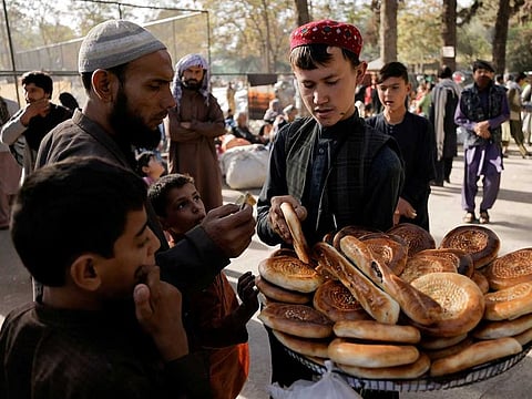 A boy sells bread at a makeshift shelter for displaced Afghan families, who are fleeing the violence in their provinces, at Shahr-e Naw park, in Kabul, Afghanistan October 4, 2021.