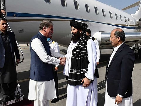 This handout photograph taken on October 21, 2021 and released by the Pakistan Foreign Office shows Afghanistan's acting Foreign Minister Amir Khan Muttaqi (2R) receiving Pakistan's Foreign Minister Shah Mahmood Qureshi (3L) upon his arrival at the airport in Kabul.