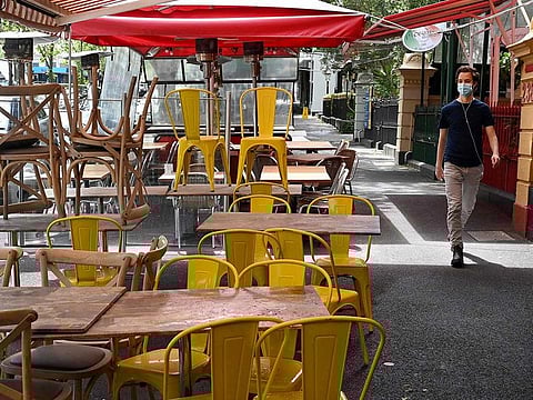 A pedestrian walks past a cafe being prepared for opening in Melbourne on October 21, 2021, ahead of the expected lifting of coronavirus restrictions in one of the world's most locked-down cities at midnight.