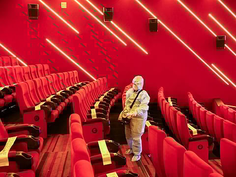 A worker sanitizes seats inside a movie theatre ahead of its reopening in Mumbai, on October 20, 2021.