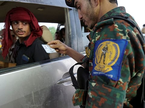 A police trooper checks an ID card of a driver at a checkpoint on the outskirts of Marib city on October 20, 2021.