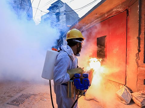 Fire blows from a fogging machine as a worker sprays fumigation vapour to stem the spread of dengue virus along a street in Peshawar.