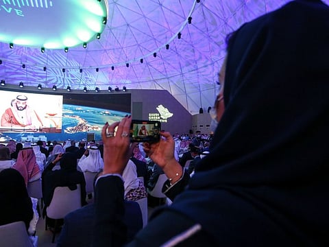A woman records while Saudi Arabia's Crown Prince Mohammad bin Salman speaks during the Saudi Green Initiative Forum to discuss efforts by the world's top oil exporter to tackle climate change in Riyadh on October 23, 2021.