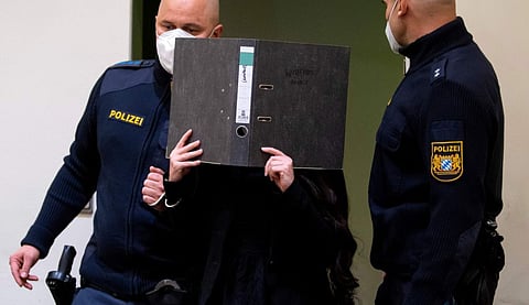 Defendant Jennifer W. arrives in a courtroom for her trial in Munich, Germany, Monday, Oct. 25, 2021. The woman from Lohne in Lower Saxony is charged with murder and war crimes. As a Daesh supporter in Iraq, she is said to have stood idly by while a small Yazidi girl was chained in a courtyard and died of thirst.