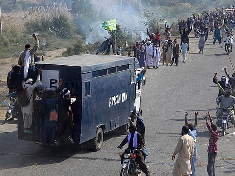 Supporters of Tehreek-e-Labiak Pakistan, a banned Islamist party, celebrate after capturing a police vehicle during their protest march toward Islamabad, on a highway in the town of Sadhuke, in eastern Pakistan, on Wednesday, October 27, 2021.