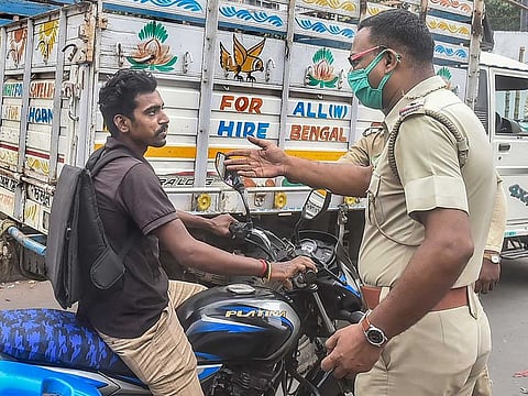 A policeman stops a bike rider for not wearing protective face mask, at a market area which has been closed for three days in the view of rise in fresh COVID-19 cases after Durga puja festivities, in South 24 Parganas, West Bengal, Thursday, Oct 28, 2021.
