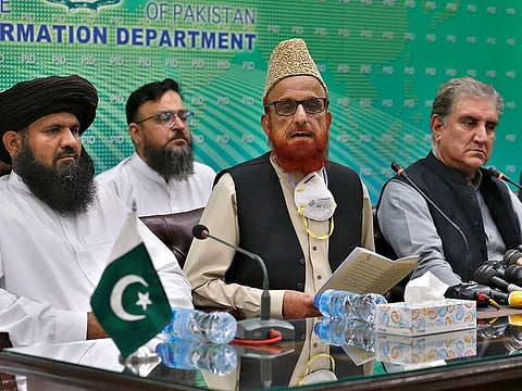 Pakistan's Foreign Minister Shah Mahmood Qureshi, right, and top religious leader Mufti Muneebur Rehman, centre, who helped negotiate an end to a protest march by Islamists, give a press conference, in Islamabad, Pakistan, Sunday, Oct. 31, 2021.
