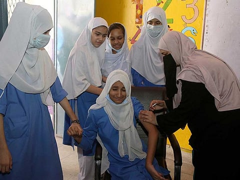 A student receives a doze of Pfizer COVID-19 vaccine from a health worker at a school in Lahore, Pakistan, Monday, Oct. 4, 2021.