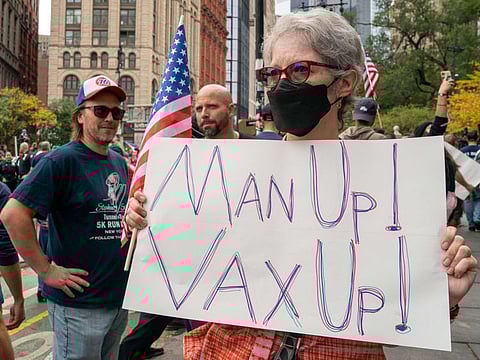 A woman holds a sign urging people to get vaccinated at an anti-vax rally on October 25, 2021 in New York City.