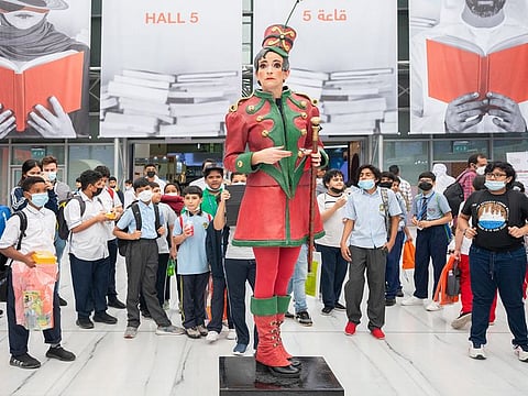 A performer mimicking a statue at SIBF 2021 at Expo Centre Sharjah draws curious children
