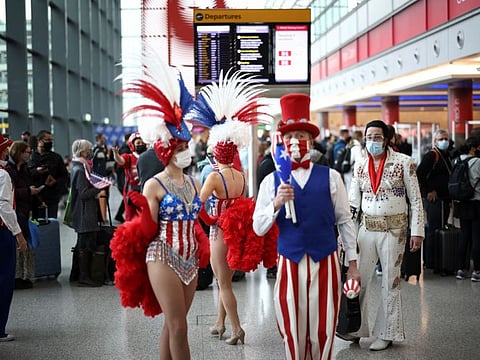 Performers engage with travellers in London on November 8, 2021, as they queue to check into Virgin Atlantic and Delta Air Lines flights at Heathrow Airport Terminal 3, following the lifting of restrictions on the entry of non-US citizens to the United States imposed to curb the spread of COVID-19.