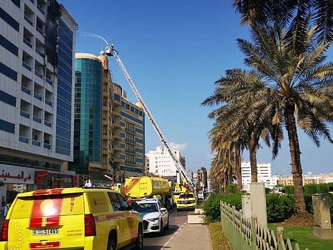 Civil Defence personnel conduct firefighting operations at the building in Al Muraqqabat that caught fire today.