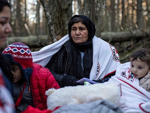 An elderly woman sits with children as the members of the Kurdish family from Dohuk in Iraq wait for the border guard patrol, near Narewka, Poland, near the Polish-Belarus border on November 9, 2021.