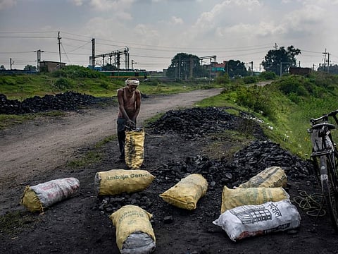 A man fills scavenged coal in sacks before selling it to traders in Dhanbad, an eastern Indian city in Jharkhand state, Friday, Sept. 24, 2021. No country will see energy needs grow faster in coming decades than India, and even under the most optimistic projections part of that demand will have to be met with dirty coal power — a key source of heat-trapping carbon emissions.