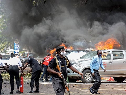 People extinguish fire on cars caused by a bomb explosion near Parliament building in Kampala, Uganda, on November 16, 2021.