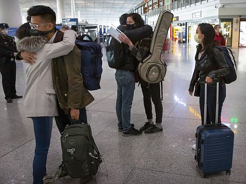 Wall Street Journal reporters embrace colleagues before their departure at Beijing Capital International Airport in Beijing, on March 28, 2020. China and the US have agreed to ease restrictions on each other's media workers amid a slight easing of tensions between the two sides.