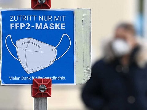 A sign informs people to cover mouth and nose with an FFP2 mask in front of a COVID-19 pandemic test centre in the small village of Unterschleissheim near Munich, southern Germany, on November 18, 2021, amid the ongoing coronavirus Covid-19 pandemic. - New infections over the last 24 hours soared to another record of 65,371, data from the Robert Koch Institute (RKI) showed, part of a spike Chancellor Angela Merkel has called "dramatic".