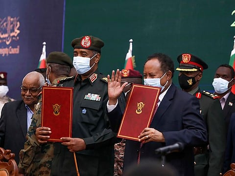 Sudan’s top general Abdel Fattah Al-Burhan, centre left, and Prime Minister Abdalla Hamdok hold documents during a ceremony to reinstate Hamdok, who was deposed in a coup last month, in Khartoum, Sudan, Sunday Nov. 21, 2021.