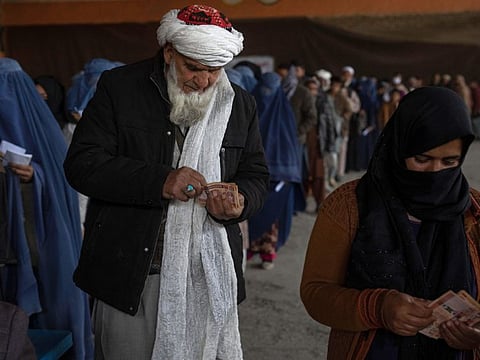 People count banknotes during a money distribution organised by the World Food Programme in Kabul, on November 20, 2021.