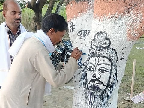 Premchand Sahani painting on a roadside tree in West Champaran district.