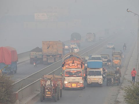 Vehicles move amid dense smog in Lahore on November 24, 2021.