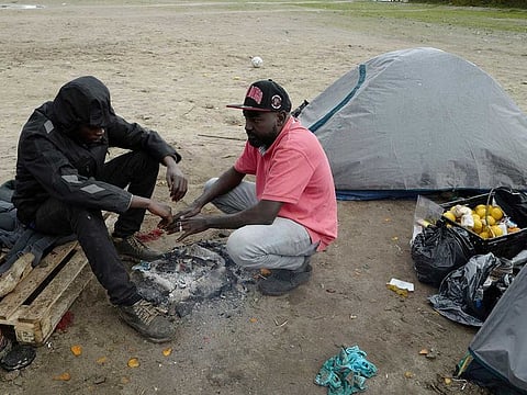 Migrants warm up around a fire in a makeshift camp outside Calais, northern France, Saturday, Nov. 27, 2021.