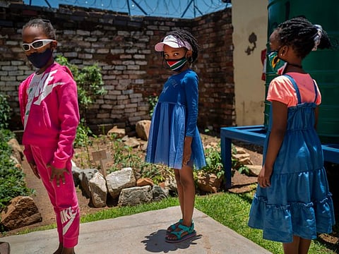 Pupils lineup to enter their classroom at the Kgololo Academy in Johannesburg's Alexandra township on November 30, 2021.