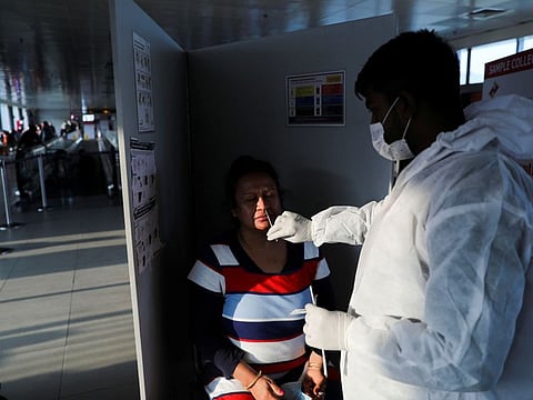 A healthcare worker collects a test swab sample from a woman at the Indira Gandhi International Airport in New Delhi, on November 29, 2021.