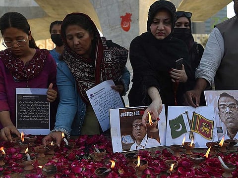 Members of the Human Rights Council of Pakistan place  oil lamps to pay tribute beside a photograph of late Sri Lankan factory manager Priyantha Kumara, in Karachi on December 5, 2021, after he was beaten to death and set ablaze by a mob who accused him of blasphemy.