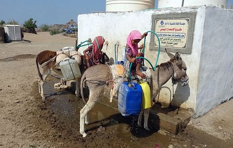 Girls fill up a tethered jerry can with water from a cistern at a makeshift camp for people who fled battles between Yemen's Al Huthi militia and the Saudi-backed government forces in the area of Al Jarrahi, near the conflict zone in the western Hodeida province on December 4, 2021.