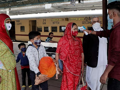 A health worker checks the body temperature of passengers arriving at a railway station as a precaution against COVID-19 before allowing them to enter the city, in Mumbai, on December 7, 2021.