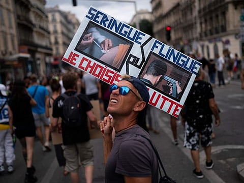 A protester marches with a sign reading in French "syringe or gun" during an anti-lockdown demonstration in Marseille, southern France in a file photo.