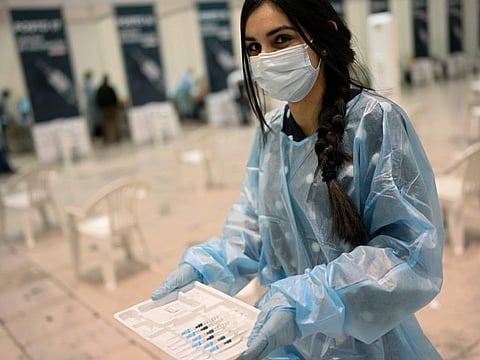 A nurse carries doses of the Pfizer vaccine against COVID-19 on the first day of a new vaccination centre in Lisbon on December 1, 2021.