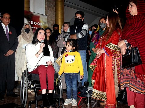 Shaukat Mukadam, father of Noor Mukadam, presenting a calligraphic work done by his daughter to an artist at an exhibition organized by the Pakistan National Council of the Arts.