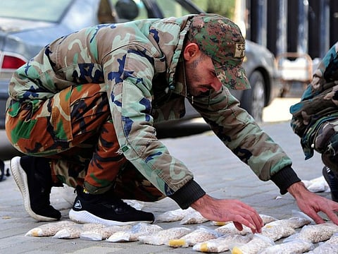 In this photo released by the Syrian official news agency Sana, a Syrian soldier displays Captagon pills, in rural Damascus.