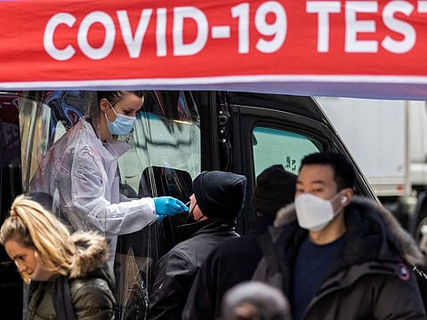 A man is tested for the coronavirus disease (COVID-19) at a mobile COVID-19 testing unit, as pedestrians make their way in the sidewalk during the spread of the Omicron coronavirus variant in Manhattan, New York, U.S., December 8, 2021.