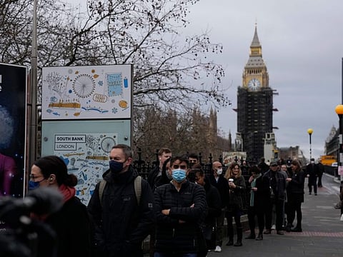 People queue to go for COVID-19 booster jabs at St Thomas' Hospital, backdropped by the scaffolded Elizabeth Tower, known as Big Ben, and the Houses of Parliament, in London, on Monday.