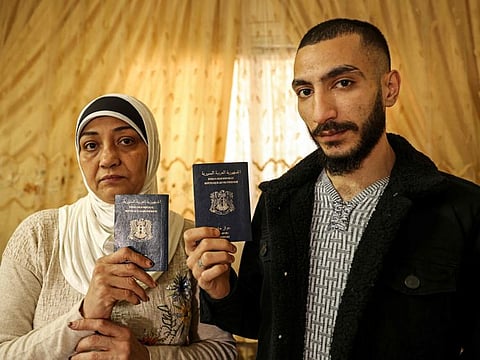 Syrian refugees Lina Mustafa Hassoun and her son Nawras Deeb pose with their expired Syrian passports in a house in Gaza City on December 5, 2021.