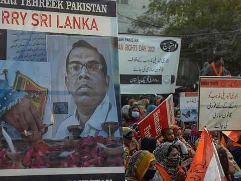 Activists from Rawadari Tehreek hold placards with pictures of the slain Sri Lankan factory manager who was beaten to death and set ablaze by a mob in Pakistan during a march held in Lahore on December 10, 2021 on the International Human Rights Day.