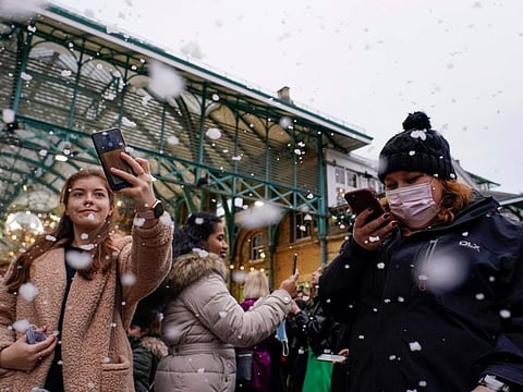 People enjoy the fake snow in Covent Garden, in London, on Dec. 16, 2021.