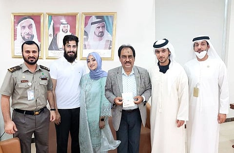 Pakistani expat Madiha Farman with his father Farman Hyder (forth from left) posing for a photograph with officials after receiving her Golden Visa in Abu Dhabi.